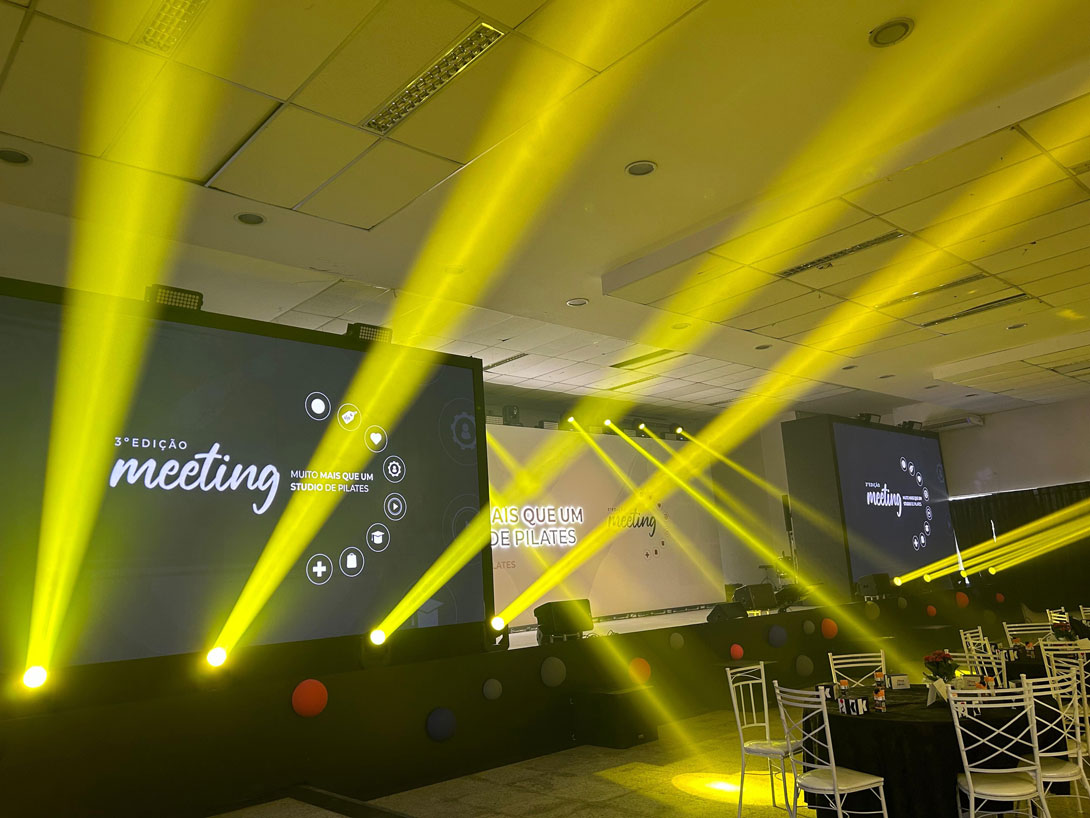 Iluminação cênica em tons de amarelo criando uma atmosfera sofisticada em um evento feito pela VST Produções
